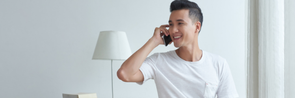 man sitting, smiling, and talking on the phone