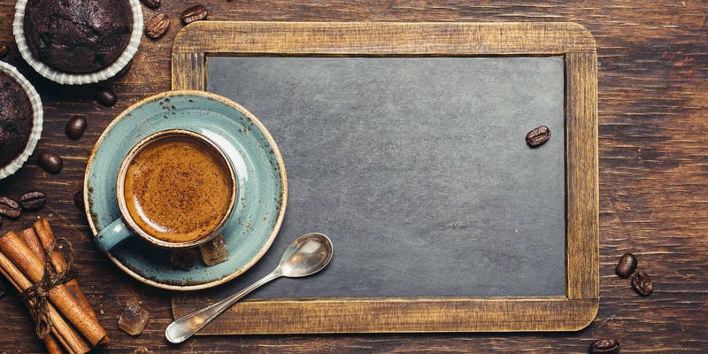 coffee mug and spoon on top of chalkboard with cinnamon on the side 