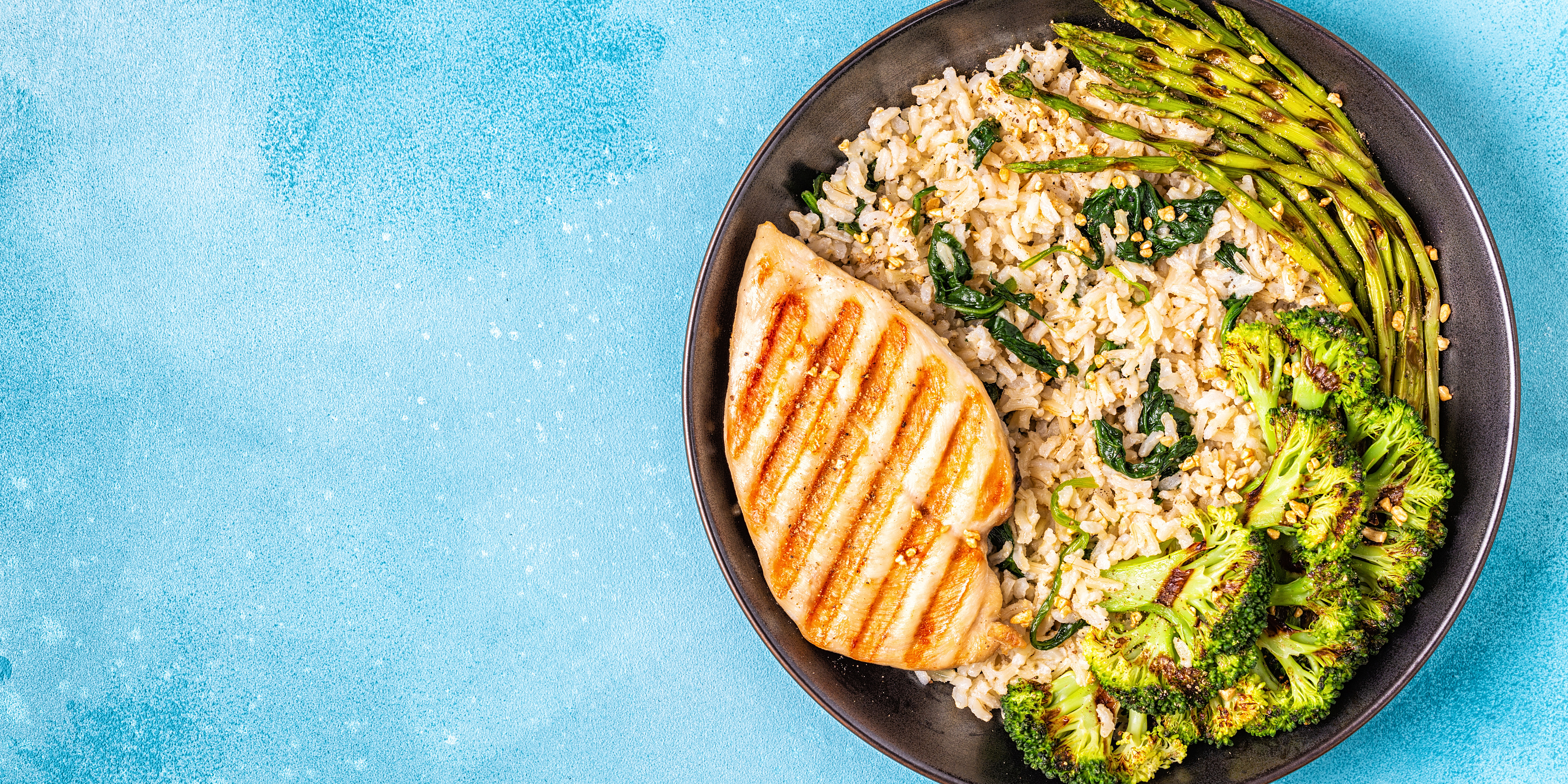 lemon chicken on plate with rice broccoli and asparagus 